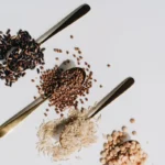Glúten: O Que É – cereais como trigo, cevada e aveia dispostos em colheres de madeira, representando alimentos relacionados ao glúten.