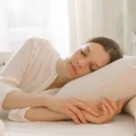 Mulher dormindo tranquilamente em uma cama confortável, ilustrando os benefícios do sono de qualidade para a saúde física e mental.