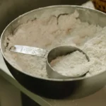 Creatina em pó com medidor dentro do recipiente, suplemento utilizado para melhorar o desempenho físico e auxiliar no ganho de força muscular.