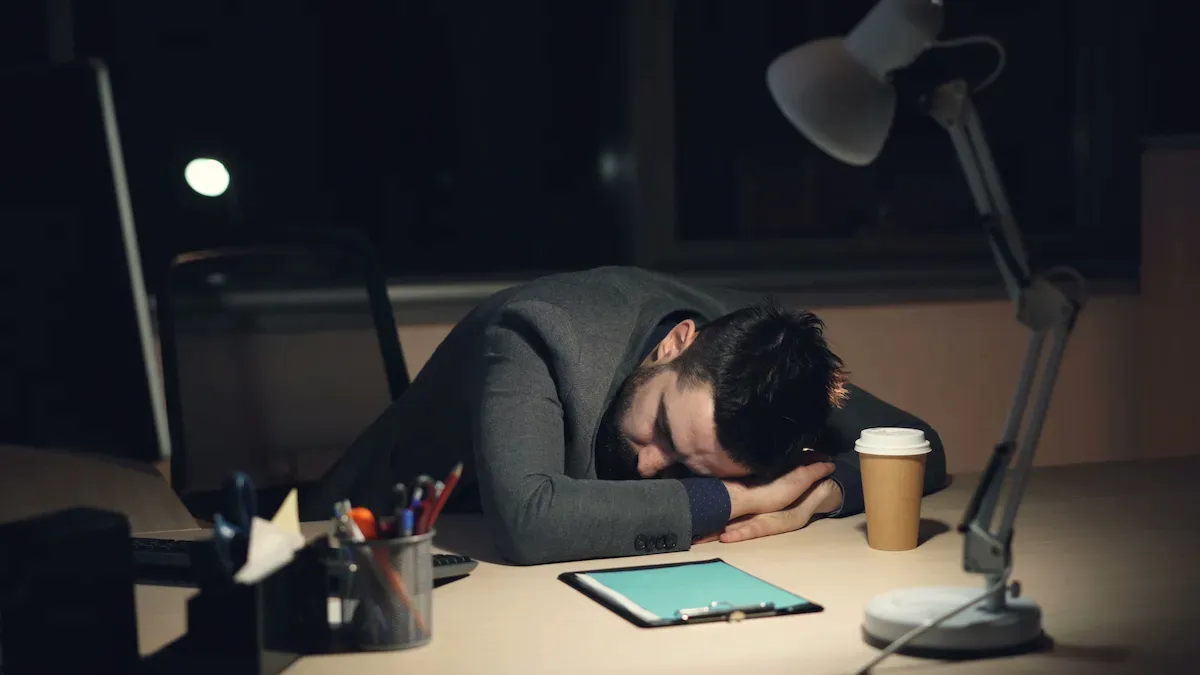 Pessoa cansada apoiando a cabeça sobre a mesa, representando um dos 7 sinais de que seu corpo está precisando descansar devido ao excesso de cansaço físico e mental.