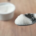 Colher com açúcar refinado representando os malefícios do açúcar e os riscos do consumo excessivo para a saúde.