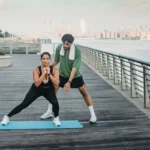 Mulher fazendo exercício ao ar livre com orientação de um personal trainer para ajudar na redução da gordura abdominal.