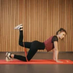 Mulher fazendo coice com miniband durante exercícios para glúteos para fortalecer e definir a musculatura dos glúteos.