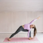 Mulher se alongando em casa para voltar a fazer exercícios depois de muito tempo parada.