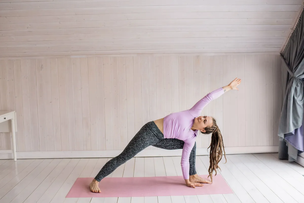 Mulher se alongando em casa para voltar a fazer exercícios depois de muito tempo parada.